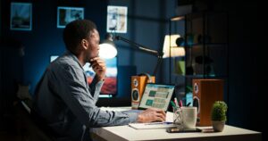 Digital marketer working on a laptop in a modern office at night.